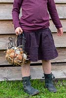 Fille portant un panier plein d'oeufs de poule dans un jardin