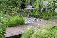 Table et chaises sur terrasse carrelée de mosaïque. 'Style and Design Garden', RHS Hampton Flower Show 2018