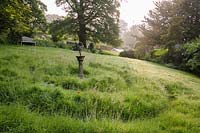 Labyrinthe d'herbe sur un terrain en pente dans un jardin de campagne.