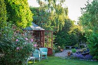 Maison d'été en bois à l'ancienne avec des chaises en osier. Little Friars Garden, Battle, Sussex, Royaume-Uni.