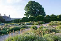 Miserden Park, Gloucestershire, été, avec des vues spectaculaires sur un parc aux cerfs et les collines des Cotswolds au-delà. Le jardin de style parterre formel avec des têtes de graines d'allium en été.