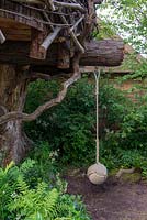 Balançoire pour enfants suspendus à une branche d'arbre sous une cabane dans les arbres - The RHS Back to Nature Garden, RHS Chelsea Flower Show 2019.