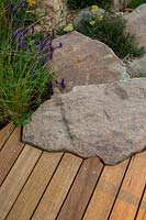 Détail de la bordure d'une promenade en bois qui a été coupée à la main pour épouser la forme d'une roche de grès rustique.