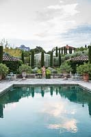 Réflexions dans la piscine avec topiaire émergeant d'une étendue de Ceratostigma. Le jardin se concentre sur les conifères parfumés - pitosfori, oliviers, lauriers roses et lonicera nitida.