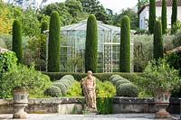Topiaire mixte sur la terrasse avec sculpture figurative. Le jardin se concentre sur les conifères parfumés - pitosfori, oliviers, lauriers roses et lonicera nitida.