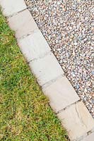 Chemin de jardin en gravier incurvé avec du gravier 'Scottish Pebbles' et bordé de pavés de grès en 'Castle Grey' contre une pelouse