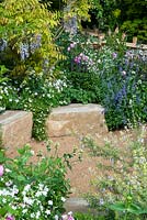 Parterre d'été de plantes vivaces avec des blocs de pierre bordant chemin de gravier - RHS Chelsea Flower Show