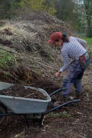 Femme jardinier enlever le compost d'un andain de compostage à long terme