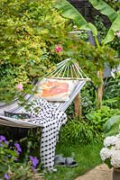 Hamac avec coussin et couverture dans petit jardin tropical