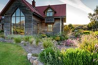 La terrasse pavée en pierre à l'extérieur de la maison est brisée par des herbes et des dieramas autour d'un parterre de fleurs surélevé contenant en grande partie des plantes sud-africaines.