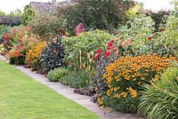 Le parterre de fleurs chaud à Bourton House, Moreton-in-Marsh en août, y compris Helenium 'Sahin's Early Flowerer', Dahlia 'Bishop of Llandaff', Kniphofia 'Mango Popsical' et des lys tigres.