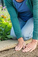 Femme utilisant ses mains pour une entreprise douce autour de graines de kalette semées