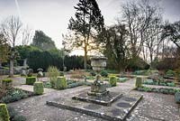 Le jardin de loisirs avec une urne en pierre et une boîte coupée panachée en son centre, Rodmarton Manor, Glos, Royaume-Uni.