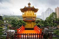 Entrée du pavillon octogonal de la perfection absolue avec son pont rouge Zi-Wu, flanqué de deux Podocarpus macrophyllus matures - pin bouddhiste. L'étang de lotus et la cascade et les immeubles de grande hauteur au-delà