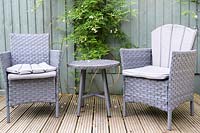 Terrasse en bois avec fauteuils et petite table de la même couleur que la clôture peinte
