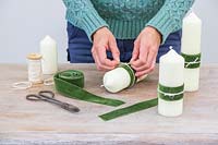 Femme ajoutant un ruban vert velouté décoratif et ficelle crème à la bougie pilier