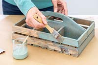 Femme à l'aide d'un pinceau pour peindre la boîte en bois avec poignée une nouvelle couche de peinture