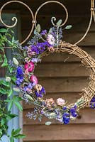 Couronne de fleurs séchées - bleu et rose suspendu à un cadre décoratif en métal