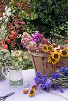 Sélection de fleurs séchées dans le panier et d'hortensias en cruche sur table