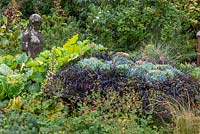 Statue à côté de l'auge en pierre plantée d'Ophiopogon planiscapus 'Nigrescens'