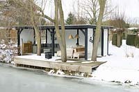 Maison d'été avec des meubles de salon confortables près du lac gelé au milieu d'un sol enneigé