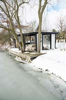 Maison d'été avec mobilier de salon confortable au bord d'un lac gelé au milieu d'une zone couverte de neige