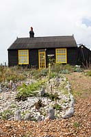 Cottage et jardin sur une plage de galets, parterre de pierres blanches avec des plantes