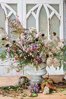 Arrangement floral d'automne dans une urne avec des fleurs séchées et fourragées inc échinacée, clématite, fougère, hortensias, échinops.