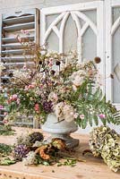 Arrangement floral d'automne dans l'urne avec des fleurs séchées et fourragées inc échinacée, clématite, fougère, hortensias, échinops