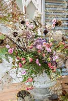 Arrangement floral d'automne dans l'urne avec des fleurs séchées et fourragées inc échinacée, clématite, fougère, hortensias, échinops