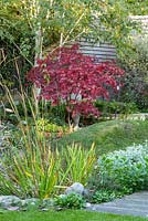 Jardin de la ville nécessitant peu d'entretien Vue sur le jardin avec Acer palmatum 'Bloodgood' et la sculpture de Mike Speller