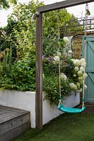 Family Small Hackney Garden - balançoire et parterre de fleurs surélevé avec plantation d'allium, d'hortensia blanc et d'Erigeronby Earth Designs