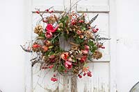 Couronne florale avec Hippeastrum, pommes sauvages, pommes de pin, fleurs d'hortensia séchées. Stylisme: Marieke Nolsen