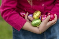 Enfant tenant des oeufs en chocolat colorés à Pâques