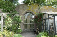 Grande vieille porte en bois dans le vieux jardin clos avec serre et Rosa - rosier grimpant,