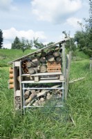 Hôtel d'abeilles fait avec des troncs d'arbres, des pots de fleurs en terre cuite au verger dans l'herbe.