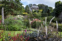 Actea simplex 'Black Negligee' devant Grand jardin en pente divisé avec terrasses et haies à la fin de l'été