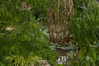 Une structure en grille de bambou laminé entourée d'une piscine remplie de plantes aquatiques dans le Guangzhou Chine : Guangzhou Garden, lauréat du prix du meilleur jardin d'exposition au RHS Chelsea Flower Show 2021