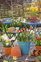 Espace détente sur terrasse en bois avec fleurs printanières en pots.