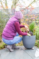 Femme remplissant les trous dans le pot avec du compost