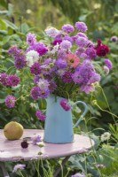 Scabious mixtes, Zinnia et Dianthus affichés dans un pot en émail bleu sur la table