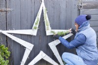 Femme plaçant des brins de cèdre sur l'étoile en bois
