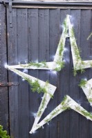 Étoile en bois avec guirlande lumineuse accrochée à un mur en bois noir