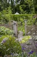 Clôture tissée Hazel menant au jardin en taillis dans le jardin du cottage