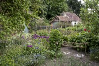 Légumes et fleurs mélangés dans le jardin de cottage, supports tissés d'usine de noisetier