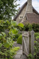 Clôture de noisetier tissé avec porte en bois rustique menant au jardin de cottage