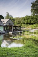Maison au bord du lac avec une terrasse en bois le long d'un côté à Am Brook Meadow dans le Devon.