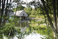 Maison au bord du lac avec une terrasse en bois le long d'un côté à Am Brook Meadow dans le Devon.
