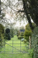 Vue sur une porte dans le jardin à Balmoral Cottage, Kent en avril caractérisé par l'if et fort topiaire.