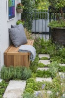 Un jardin de balcon avec un sol végétalisé créé à partir de dalles de pavage entrecoupées d'herbes, de plantes succulentes et de vivaces.